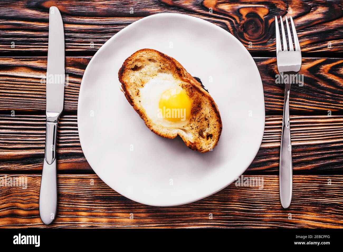 Œufs frits dans un morceau de pain blanc grillé une assiette - délicieux petit déjeuner rustique et copieux à base de produits naturels produits Banque D'Images