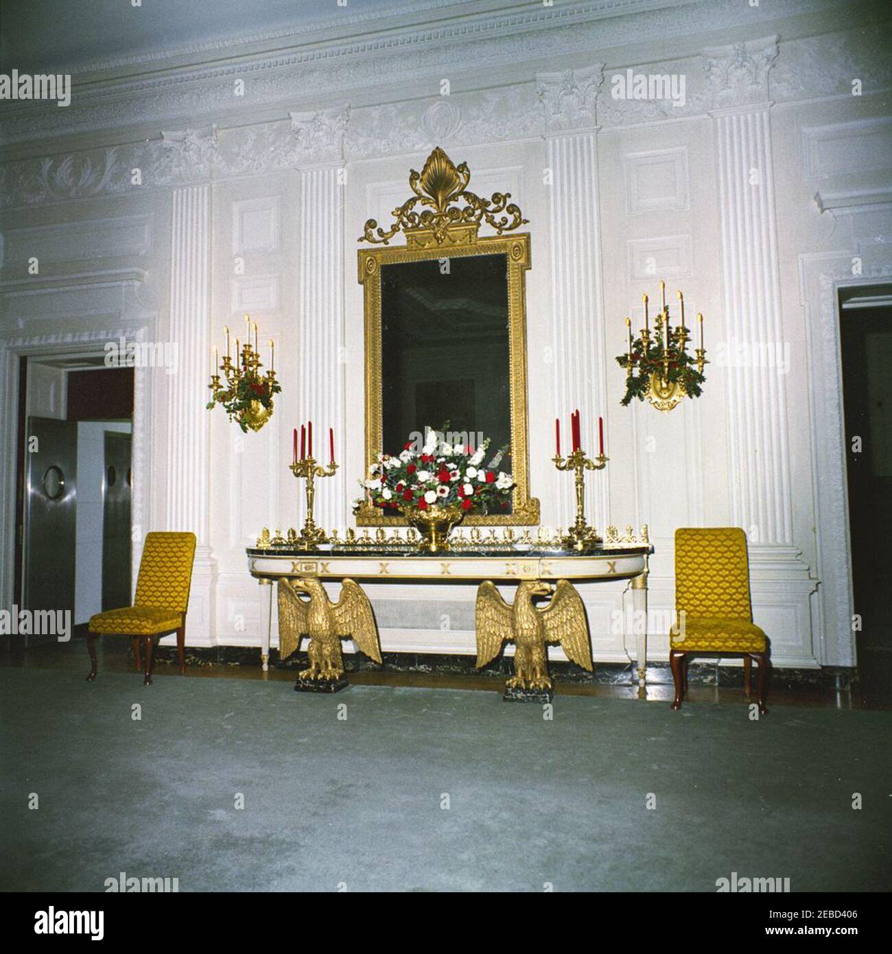 White House chambres: State Dining Room, Family Dining Room (paramètres et fleurs). Vue sur les décorations de Noël dans la salle à manger de l'État de la Maison Blanche, Washington, D.C., des fleurs et des bougies sont placées sur un panneau latéral ; le houx de Noël décore les bougies sur le mur. Banque D'Images