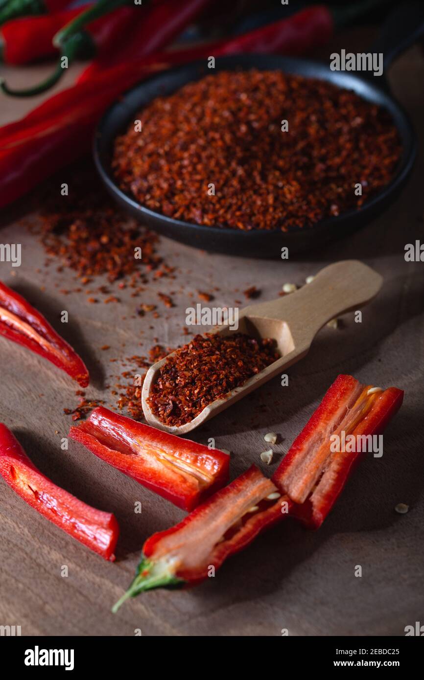 Piments rouges chauds frais avec queues vertes et flocons de piment rouge séchés dans un bol sur bois. Banque D'Images