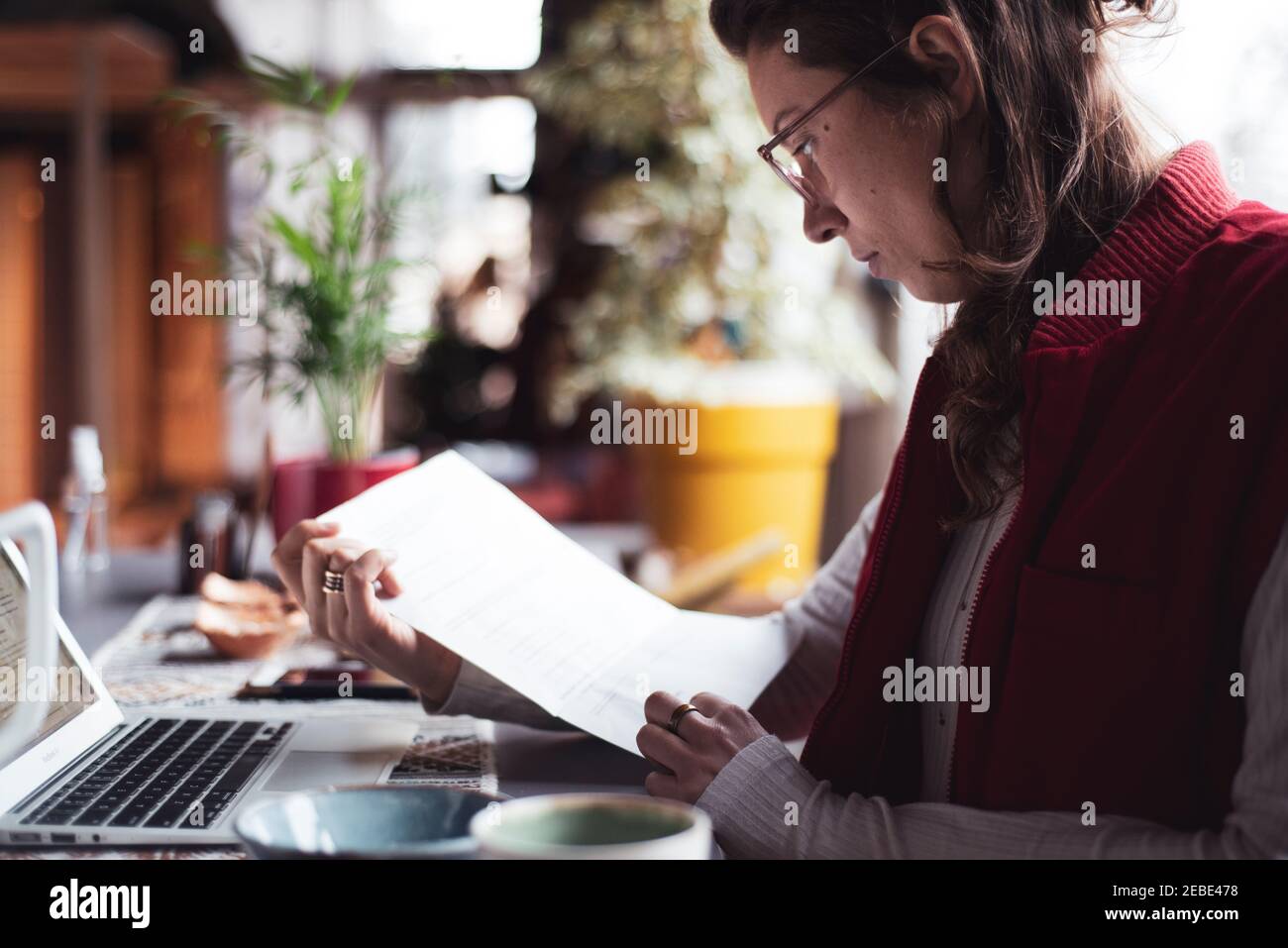femme d'affaires lit les documents avec ordinateur portable dans le bureau à domicile pendant covid Banque D'Images