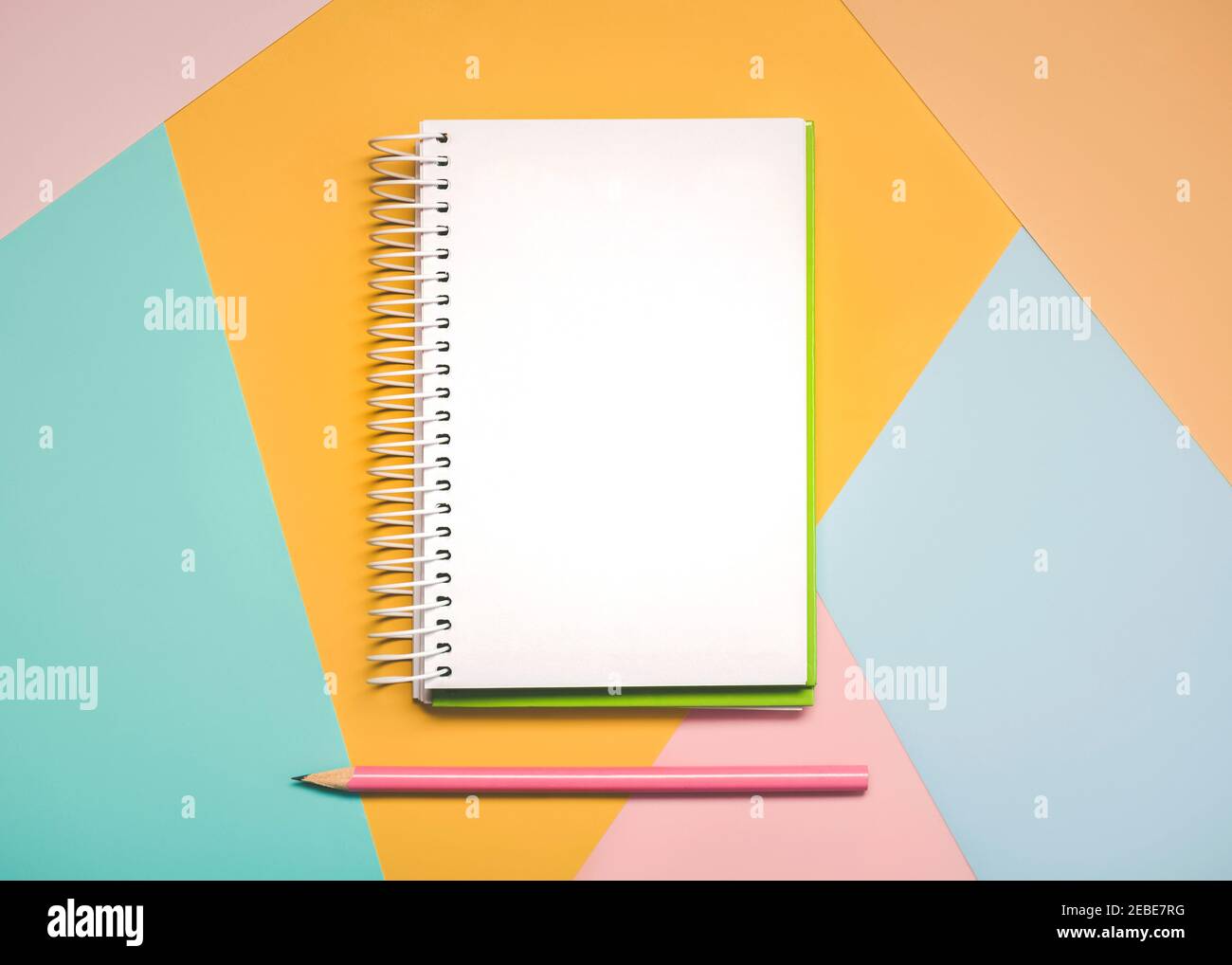 bureau avec bloc-notes en spirale et stylo rose avec copie arrière-plan d'espace sur fond coloré Banque D'Images