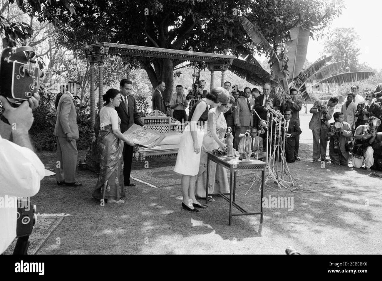 Première Dame Jacqueline Kennedyu0027s (JBK) voyage en Inde et au Pakistan: New Delhi, Delhi, Inde, Childrenu0027s Carnaval d'art à Teen Murti Bhavan, résidence du Premier ministre de l'Inde Jawaharlal Nehru. La première dame Jacqueline Kennedy présente le Carnaval d'art Childrenu2019s dans le jardin de la résidence du Premier Ministeru2019s, Teen Murti Bhavan. New Delhi, Inde. Mme Kennedy est à la table avec Indira Gandhi, fille du Premier ministre de l'Inde Jawaharlal Nehru; le Secrétaire adjoint à la presse de la Maison-Blanche, Jay W. Gildner, est en arrière-plan directement derrière Mme Gandhi. La première dame a présenté le Banque D'Images