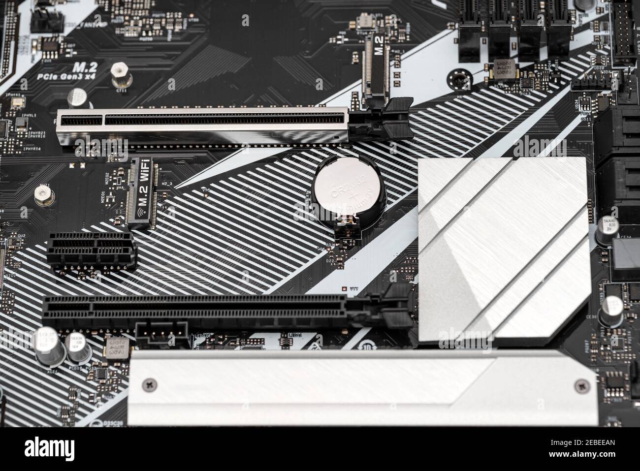Carte mère moderne d'un ordinateur de bureau de couleur noire avec connecteur PCI Express visible, batterie et dissipateurs thermiques. Banque D'Images