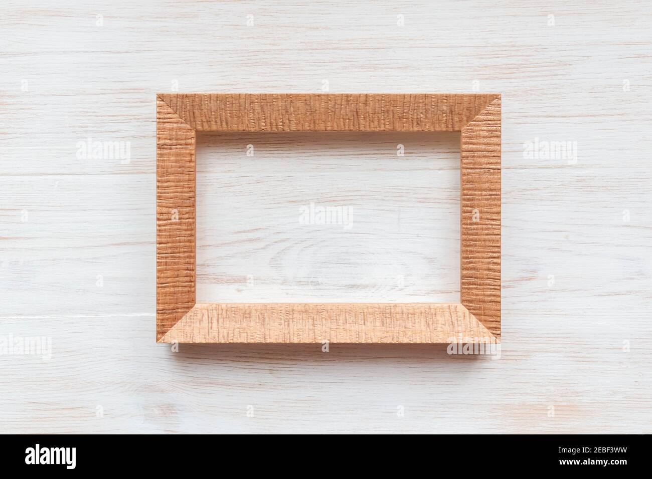 Cadre en bois vide pour la peinture, l'image ou le texte sur fond de bois blanc. Cadre d'image en bois vierge utilisé pour les produits exposés isolés sur l'arrière-plan. Banque D'Images