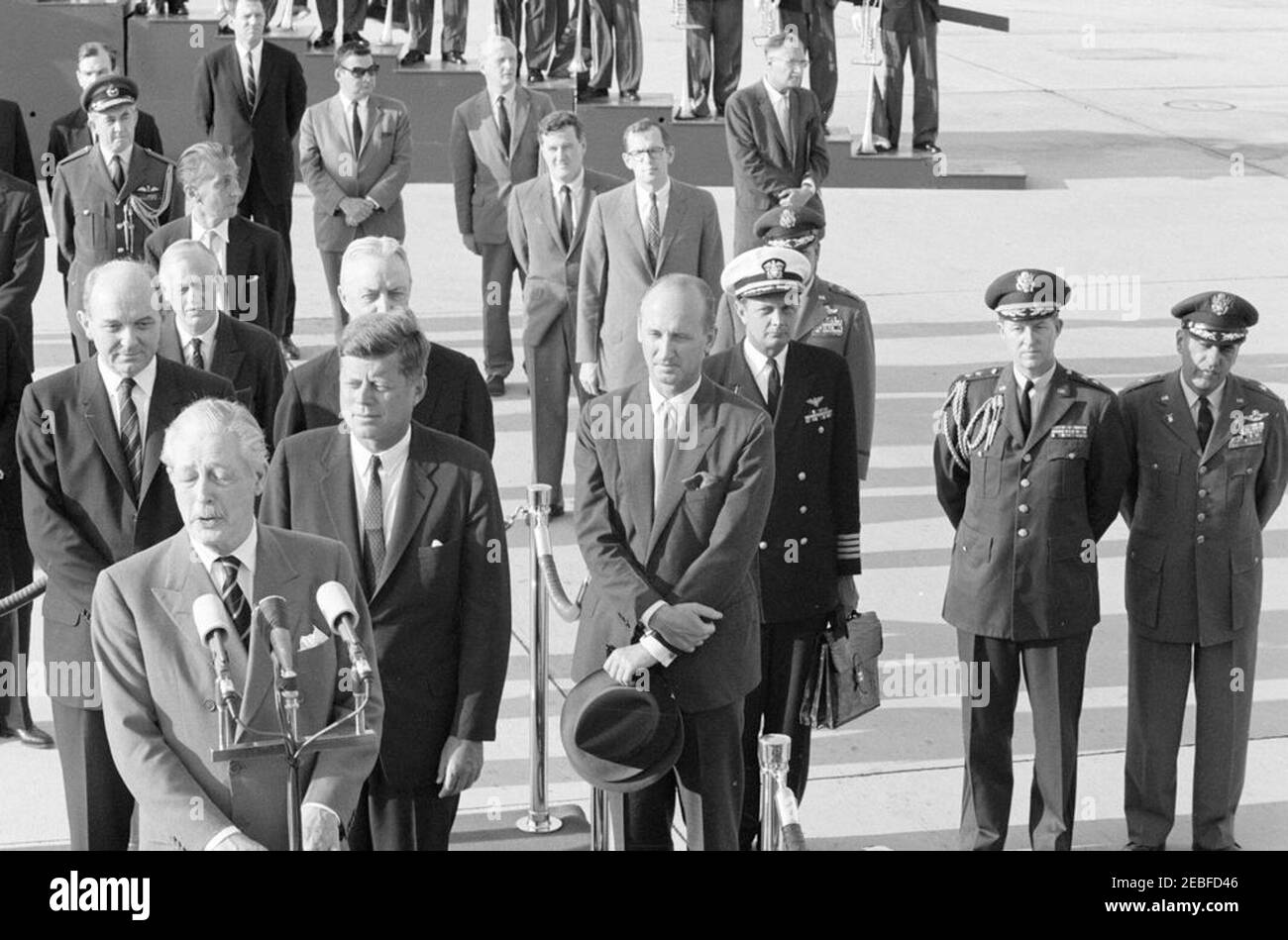 Cérémonies d'arrivée pour Harold Macmillan, Premier ministre de Grande-Bretagne, 4 h 50. Le Premier ministre de la Grande-Bretagne, Harold Macmillan, prononce des remarques lors des cérémonies d'arrivée en son honneur. Debout sur la plate-forme d'examen (G-D): Le secrétaire d'État, Dean Rusk; le premier ministre Macmillan (à micros); le président John F. Kennedy; l'ambassadeur des États-Unis en Grande-Bretagne, David K. E. Bruce (partiellement caché derrière le président Kennedy); et le chef du protocole, Angier Biddle Duke. Également en photo : Secrétaire du Cabinet des PMu2019s, Sir Norman Brook; Ministre de l'ambassade britannique, Lord Hood (Viscount Banque D'Images