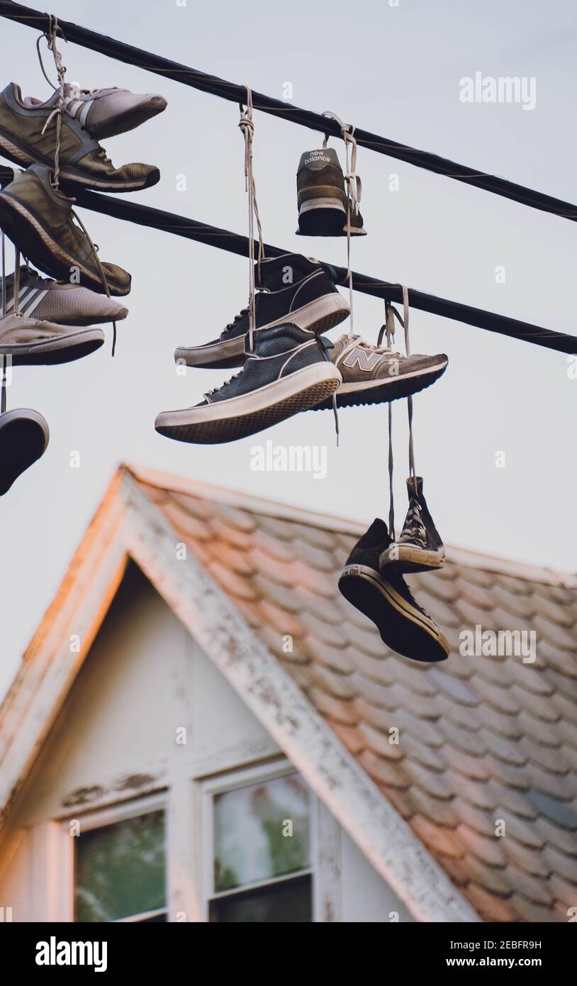 Chaussures suspendues sur la ligne téléphonique au coucher du soleil Banque D'Images