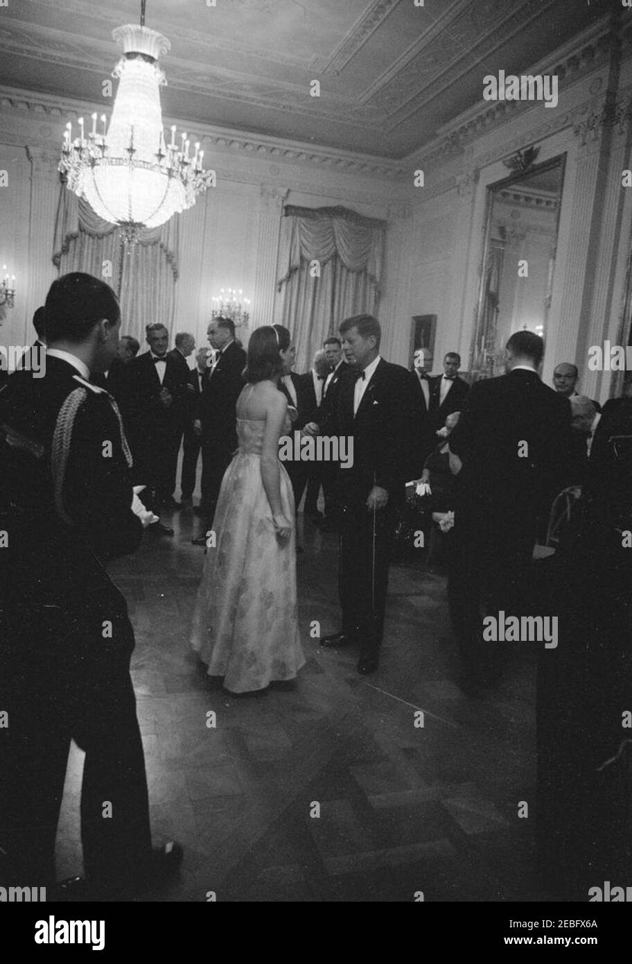 Dîner en l'honneur des lauréats du prix Nobel, 8:00. Le président John F. Kennedy visite un invité non identifié (de retour à la caméra) dans la salle East lors d'un dîner en l'honneur des lauréats du prix Nobel de l'hémisphère occidental. Les lauréats du prix Nobel sont : le physicien de l'Université de Stanford, le Dr Felix Bloch; le président de la Commission de l'énergie atomique, le Dr Glenn T. Seaborg; le rhumatologue de la clinique Mayo, le Dr Philip S. Hench; l'auteur, Pearl S. Buck; Et président du Département de biochimie de l'École de médecine de l'Université de Stanford, le Dr Arthur Kornberg. White House, Washington, D.C. Banque D'Images