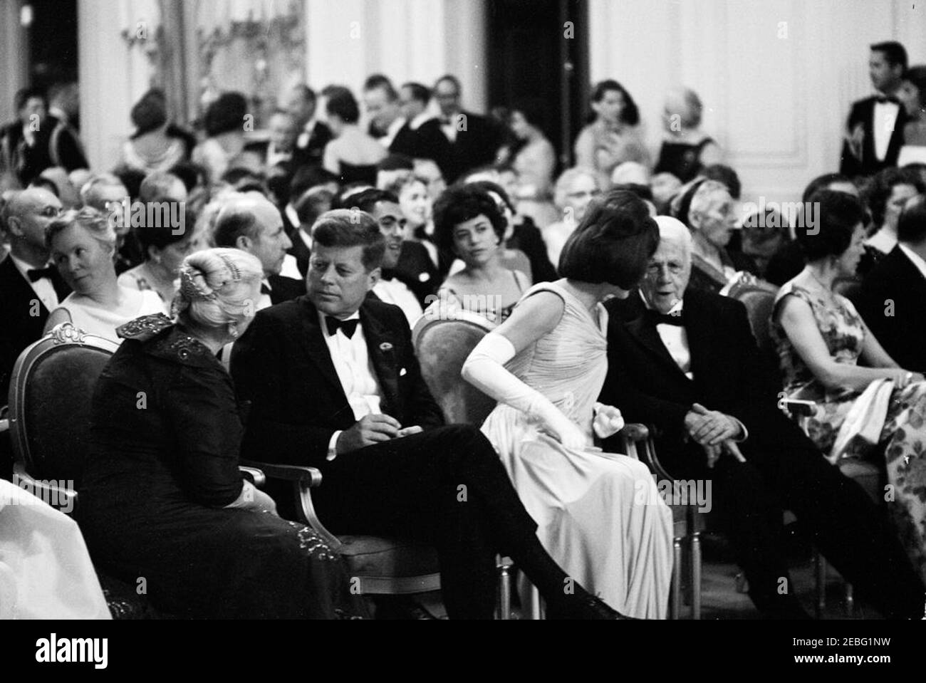 Dîner en l'honneur des lauréats du prix Nobel, 8:00. Le Président John F. Kennedy et d'autres se réunissent dans la salle de l'est pour assister à une lecture par l'acteur, Frédéric March, d'extraits des œuvres des lauréats du prix Nobel américain lors d'un dîner en l'honneur des lauréats du prix Nobel de l'hémisphère occidental. Visite du président Kennedy (au centre à gauche) avec l'auteur du prix Nobel Pearl S. Buck; visite de la première dame Jacqueline Kennedy (au centre à droite) avec le poète et nominé du prix Nobel Robert Frost. Également en photo : Geneviève Jemtegaard Calvin; biochimiste lauréat du prix Nobel de la University of California, Berkeley, Banque D'Images