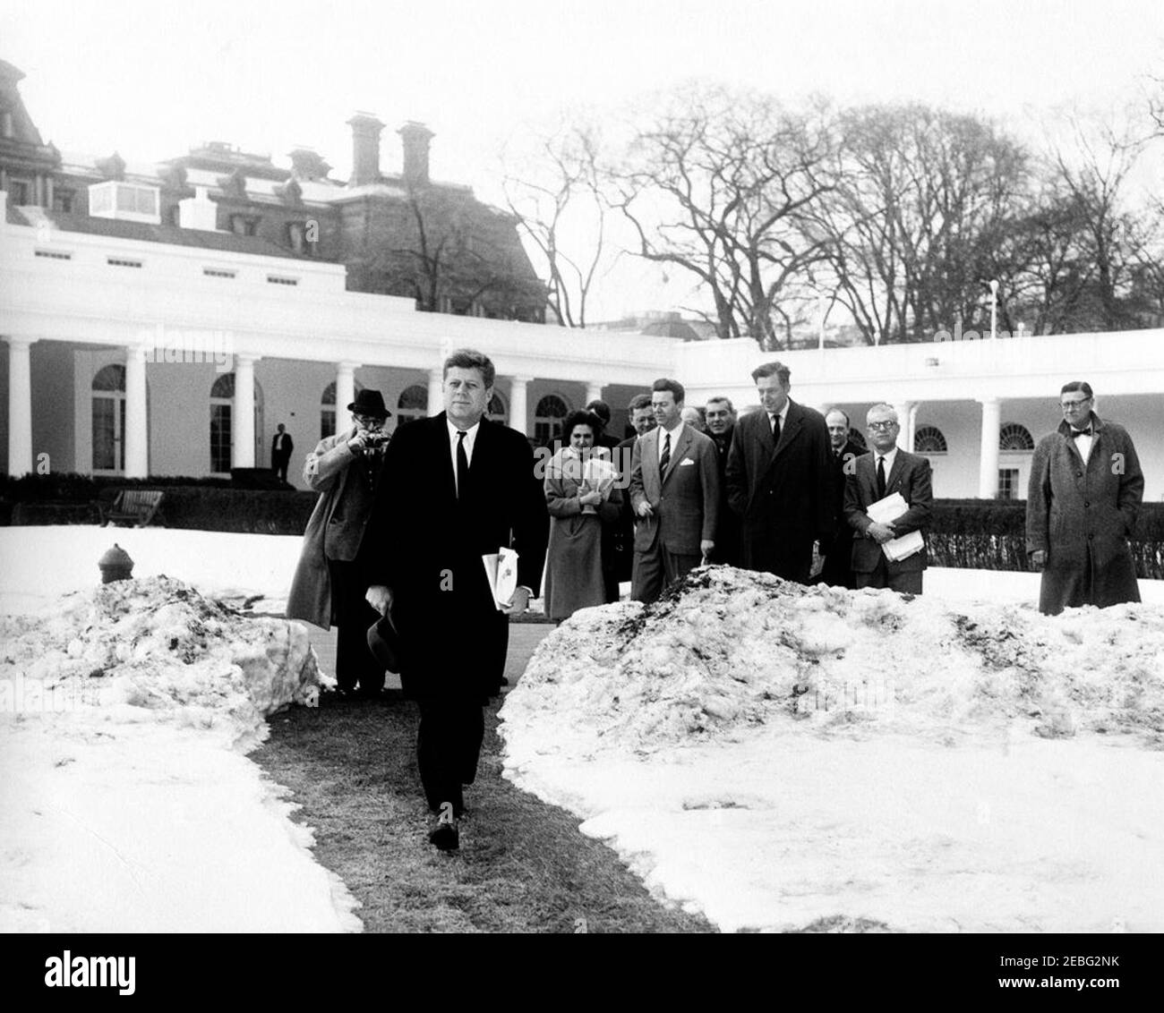 Le président Kennedy quitte la Maison Blanche en hélicoptère, à 12:35. Le président John F. Kennedy quitte la Maison Blanche pour Glen ora à Middleburg, en Virginie. Le Président Kennedy traverse un chemin dégagé de neige sur la pelouse sud, Maison Blanche, Washington, D.C. Reporters, y compris la correspondante de la Maison Blanche pour United Press International (UPI) Helen Thomas (derrière et à droite du Président), regardez le départ du Président du Conseil de l'ONU, 0027s; Le chef Gardener de la Maison Blanche, Robert M. Redmond, se trouve tout à droite. Banque D'Images