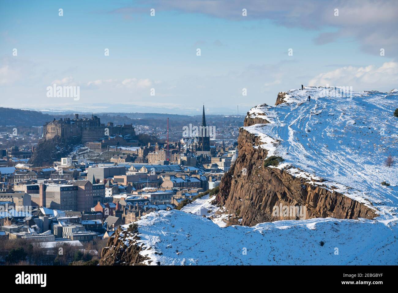 Vue sur les rochers de Salisbury couverts de neige en hiver dans Holyrood Park avec le château d'Édimbourg à l'arrière, Edimbourg, Écosse, Royaume-Uni Banque D'Images
