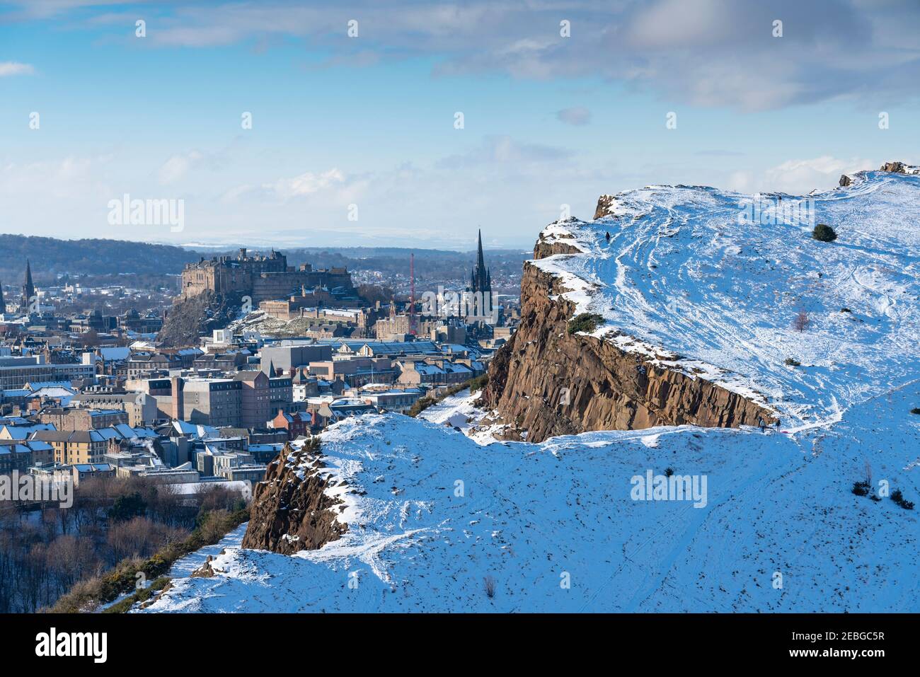 Vue sur les rochers de Salisbury couverts de neige en hiver dans Holyrood Park avec le château d'Édimbourg à l'arrière, Edimbourg, Écosse, Royaume-Uni Banque D'Images