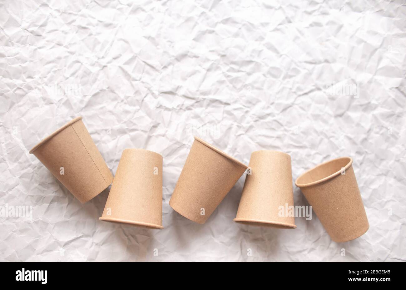gobelets en papier kraft jetables posés sur du papier froissé gris dans la répétition géométrique Banque D'Images