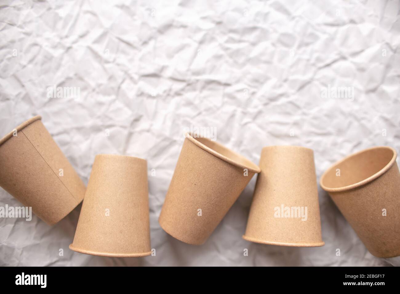 gobelets en papier kraft jetables posés sur du papier froissé gris dans la répétition géométrique Banque D'Images