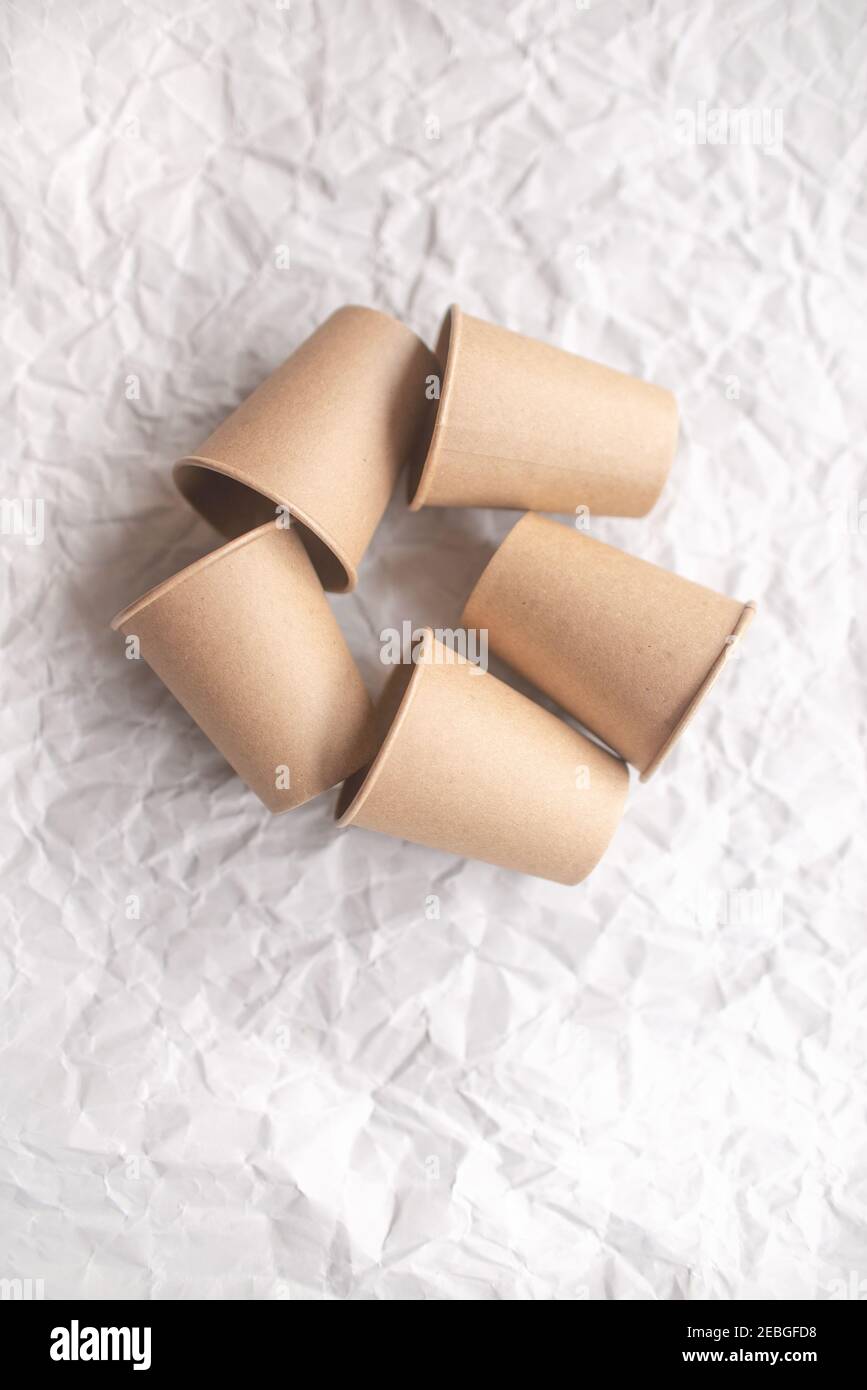 gobelets en papier kraft jetables posés sur du papier froissé gris dans la répétition géométrique Banque D'Images