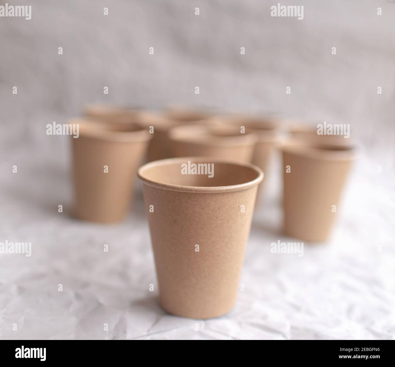 gobelets en papier kraft jetables posés sur du papier froissé gris dans la répétition géométrique Banque D'Images