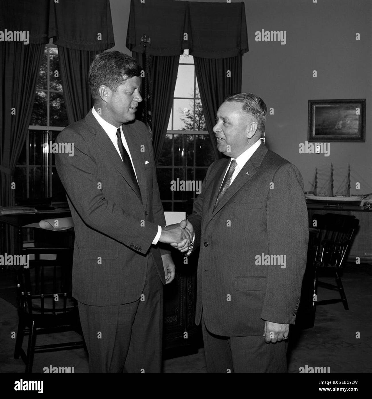 Visite des membres de la Commission de l'éducation politique (COPE) et de l'AFL-CIO (Fédération américaine du travail et Congrès des organisations industrielles), 5:45. Le Président John F. Kennedy tremble la main avec un homme non identifié (à droite) lors d'une visite avec les délégués à une conférence sur l'inscription des électeurs parrainée par la Commission de l'éducation politique (COPE) de la Fédération américaine du travail et du Congrès des organisations industrielles (AFL-CIO). Oval Office, Maison Blanche, Washington, D.C. Banque D'Images