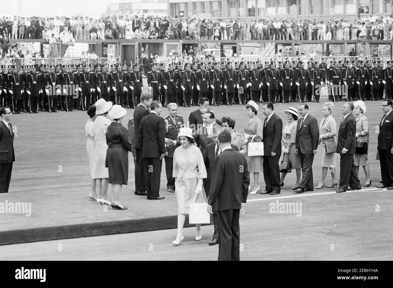 Voyage au Mexique : cérémonies d'arrivée, aéroport international de Mexico, Mexico, Mexique, 11:00. Le président John F. Kennedy salue les dignitaires du Mexique dans une ligne de réception à son arrivée à Mexico. Debout sur la plate-forme (L-R): La première Dame du Mexique, Eva Su00e1mano de Lu00f3pez Mateos; la première Dame Jacqueline Kennedy; Eva Lu00f3pez Mateos; le président Kennedy; et le président du Mexique, Adolfo Lu00f3pez Mateos. Donald Barnes, interprète du département d'État des États-Unis, se trouve à l'extrême gauche. Également en photo : Chef de l'état-major général présidentiel du Mexique, le général de division Josu00e9 Gu00f3mez H. Banque D'Images