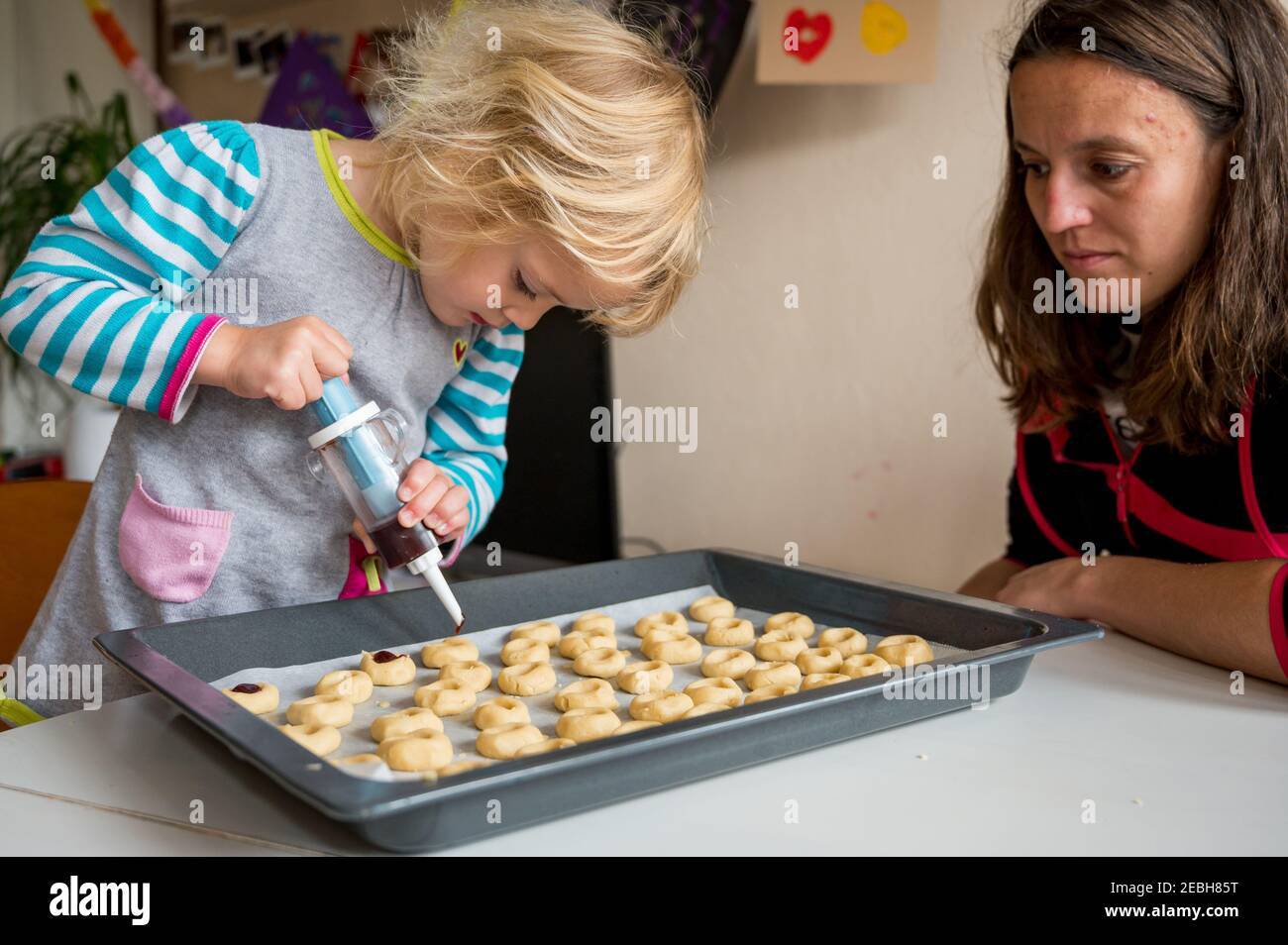 Jolie fille blonde faisant des biscuits avec sa mère. Banque D'Images