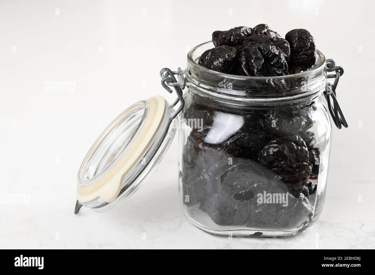 Pruneaux frais dans un pot en verre carré Fido avec refermable couvercle sur granit blanc Banque D'Images