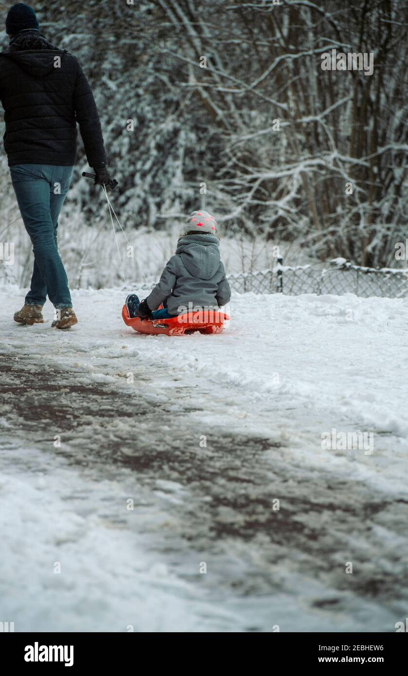 Scène d'hiver d'un homme tirant le long d'un enfant assis sur un chariot Banque D'Images