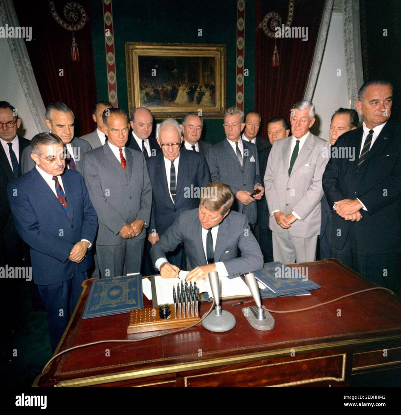 Cérémonie de signature, Traité d'interdiction des essais nucléaires, 10 h 00. Le Président John F. Kennedy signe le Traité d'interdiction des essais nucléaires dans la salle des traités de la Maison Blanche, Washington, D.C., à l'étude (L-R) : Directeur adjoint de l'Agence de contrôle des armements et du désarmement (ACDA), Adrian S. Fisher; le sénateur John O. Pastore (Rhode Island); Le sous-secrétaire d'État aux Affaires politiques, W. Averell Harriman; le sénateur George A. Smathers de la Floride (surtout caché); le sénateur J. William Fulbright (Arkansas); le secrétaire d'État, Dean Rusk; le sénateur George D. Aiken (Vermont); le sénateur Hubert H. Humphrey (Minnesota); le sénateur Everett M. Banque D'Images