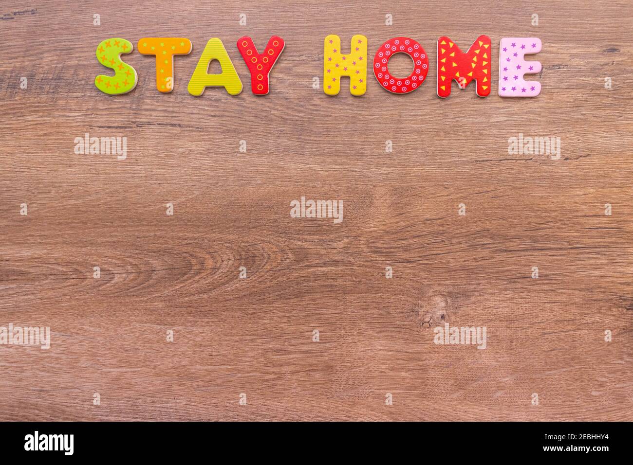 Inscription de lettres en bois RESTER À LA MAISON sur fond de bois avec espace de copie. Titre RESTEZ À LA MAISON sur fond de bois pour le maquillage. Vue de dessus. Promotion de la conception Banque D'Images