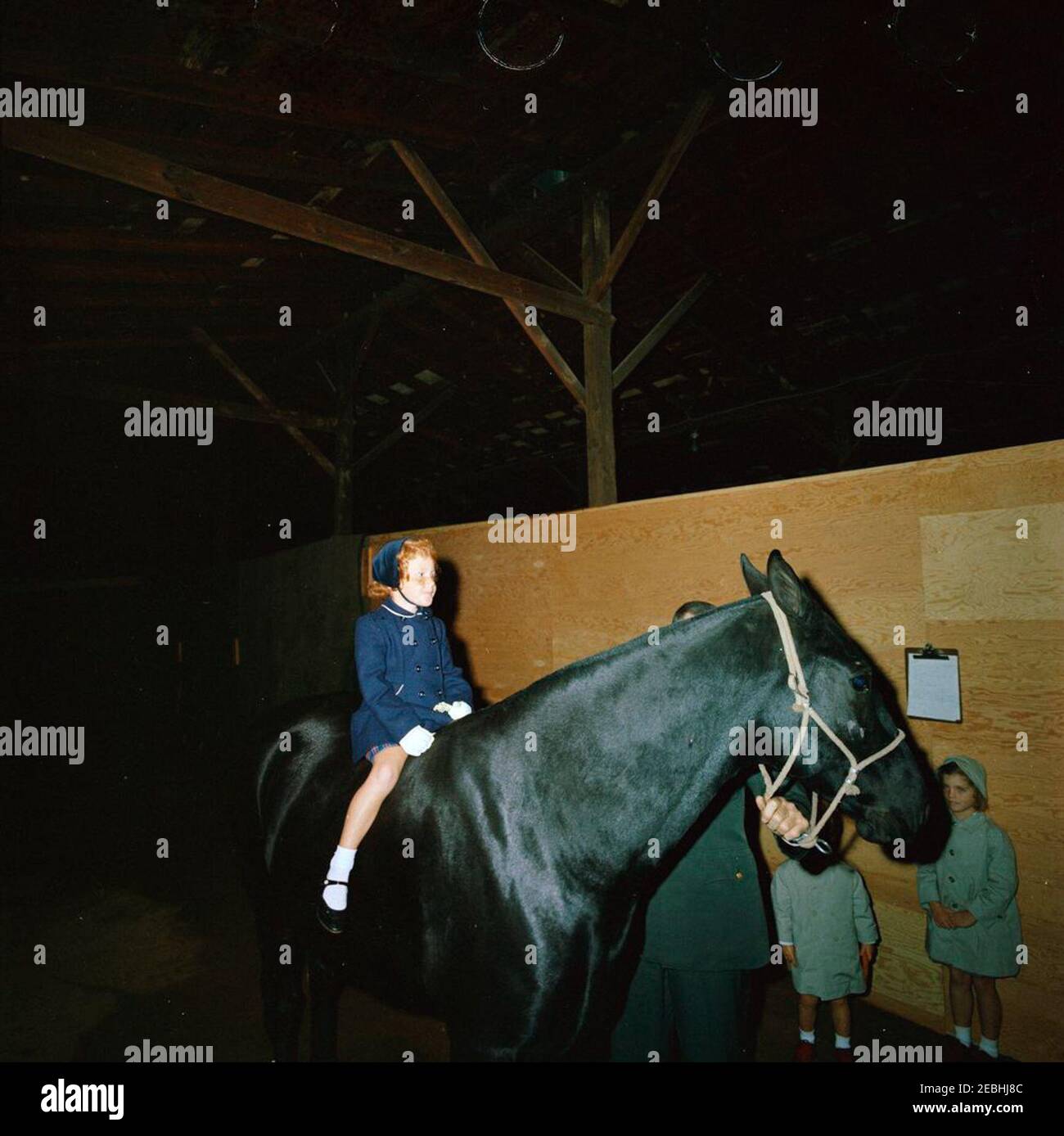 Caroline Kennedy (CBK) u0026 John F. Kennedy, Jr. (JFK, Jr.), à fort Myer stables. Une fille non identifiée se trouve à cheval lors d'une visite des écuries de fort Myer à Arlington, en Virginie. Caroline Kennedy et John F. Kennedy, Jr. (Partiellement caché), se tiennent à droite. Banque D'Images