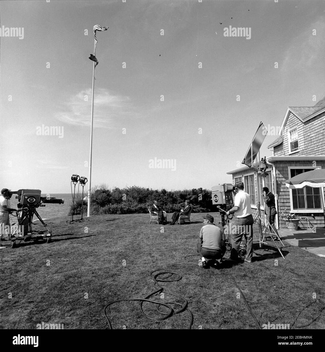 Week-end de la fête du travail au port de Hyannis : entretien avec Walter Cronkite, CBS News, pour inaugurer le premier réseau national, une émission d'informations nocturne d'une demi-heure. Columbia Broadcasting System (CBS) Evening News Anchor, Walter Cronkite (assis à gauche), interroge le président John F. Kennedy sur la pelouse à l'extérieur de la maison de Brambletyde pour inaugurer la première émission de nouvelles nocturne d'une demi-heure. Une équipe de télévision CBS filme l'entrevue. Squaw Island, Port de Hyannis, Massachusetts. Banque D'Images