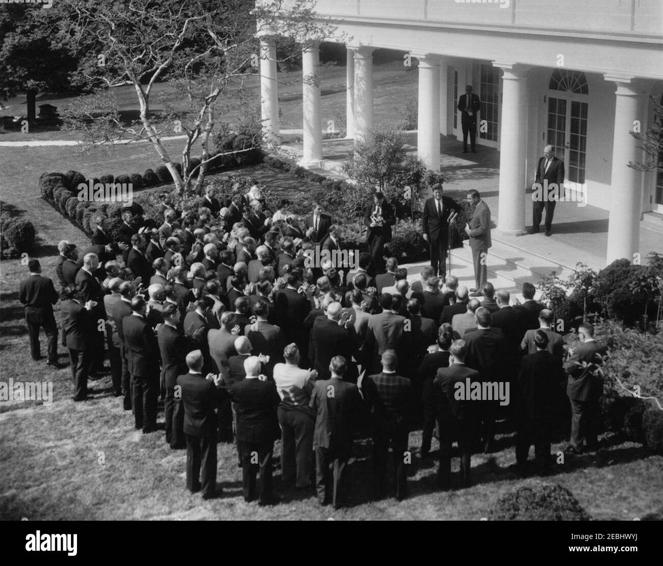 Visite du Service agricole étranger (FAS) joint, 9:45. Franklin D. Roosevelt, Jr. (À droite, à micros), de l'American polled Hereford Association, parle à un groupe d'attachés du Service agricole étranger (FAS) et de coopérateurs de produits d'élevage; le président John F. Kennedy est à gauche de M. Roosevelt. Également en photo : sous-secrétaire à l'Agriculture, Charles S. Murphy; correspondante de la Maison Blanche pour United Press International (UPI), Helen Thomas; photographe de l'United Press International (UPI), James K. W. Atherton; agent du service secret de la Maison Blanche, Toby Chandler. Jardin de roses, blanc Banque D'Images