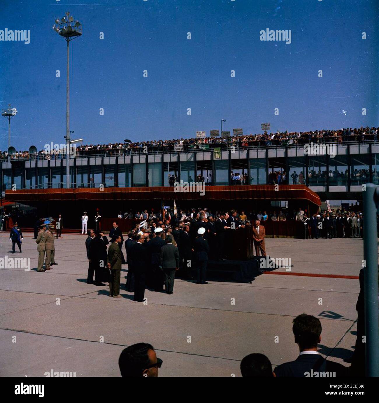 Voyage en Europe: Italie, Rome: Arrivée à l'aéroport de Fiumicino, et présentation d'un cadeau par le Président Antonio Segni au Palais Quirinale. Le président John F. Kennedy (au lectern) prononce des remarques à l'intention d'une grande foule rassemblée à l'aéroport de Fiumicino à son arrivée à Rome, en Italie. Banque D'Images