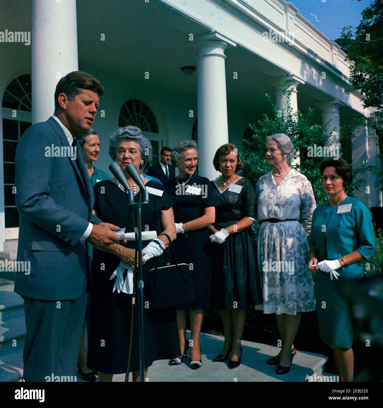 Visite des membres de la u0022Ninety-Nines,u0022 une association de pilotes féminins, 9:45. Le président John F. Kennedy fait des remarques aux membres de la Ninety-Nines, Inc., Organisation internationale des femmes pilotes, au cours d'une visite au sujet de l'émission d'un timbre commémoratif Amelia Earhart. De gauche à droite: Président Kennedy; président international, Louise M. Smith (en arrière); ancien président international, Blanche Noyes; Alice Hammond; Marion Andrews-Lopez; Fay Gillis Wells; non identifié. Ken Giannoules, agent du service secret de la Maison Blanche, est en colonnade en arrière-plan. Jardin de roses, blanc Banque D'Images