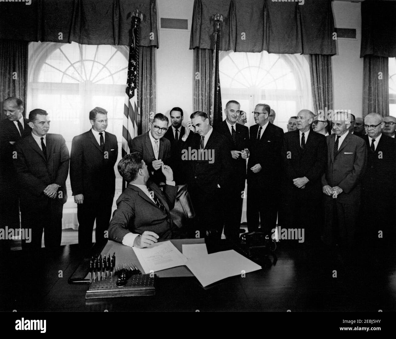 Projet de loi signant u2013 H.R. 7544, Maternal u0026 Santé infantile u0026 modifications du retard mental, 11 h 30. Le président John F. Kennedy (assis à la table) remet un stylo au représentant Wilbur D. Mills (Arkansas) après avoir signé les amendements de 1963 sur la santé maternelle et infantile et la planification du retard mental, un amendement à la Loi sur la sécurité sociale. Debout (de gauche à droite) : sous-secrétaire à la Santé, à l'éducation et au bien-être social (HEW), Ivan A. Nestingen; représentant John W. Byrnes (Wisconsin); sénateur Vance Hartke (Indiana); représentant Mills (recevant un stylo du Président Kennedy); non identifié (i Banque D'Images