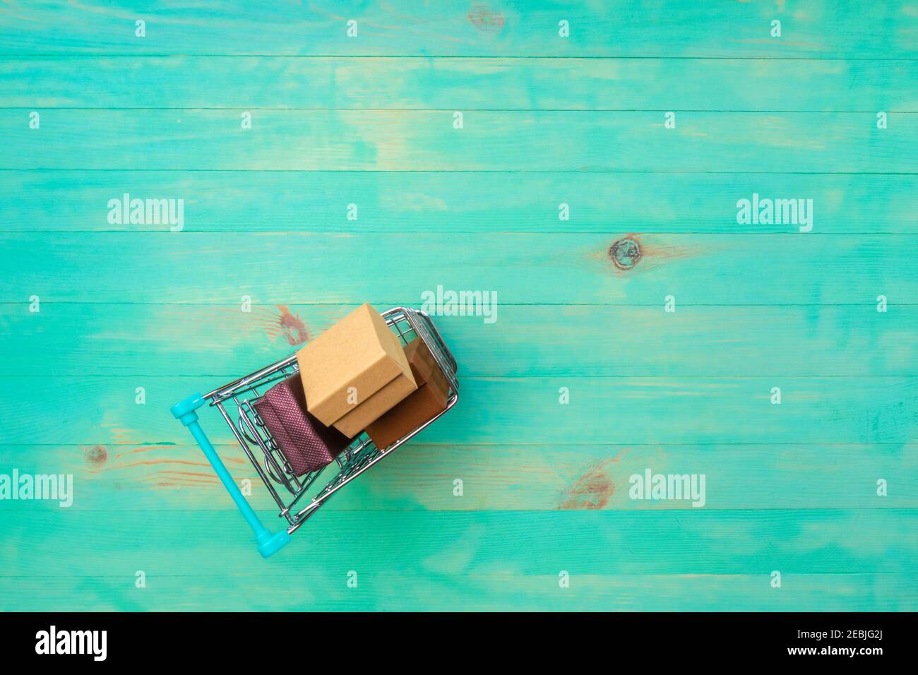 Panier rempli de boîtes sur fond de bois vintage. Petit chariot en bois turquoise. Vue de dessus, espace de copie. Banque D'Images