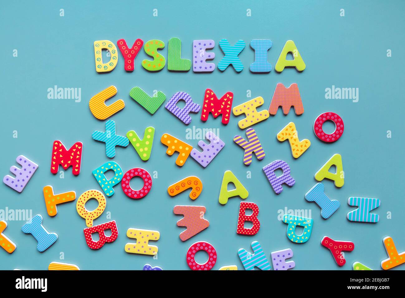 Mot de dyslexie écrit en lettres de bois et lettres éparses ci-dessous. Inscription DYSLEXIE formée de lettres colorées. Notion de difficultés de lecture. Banque D'Images