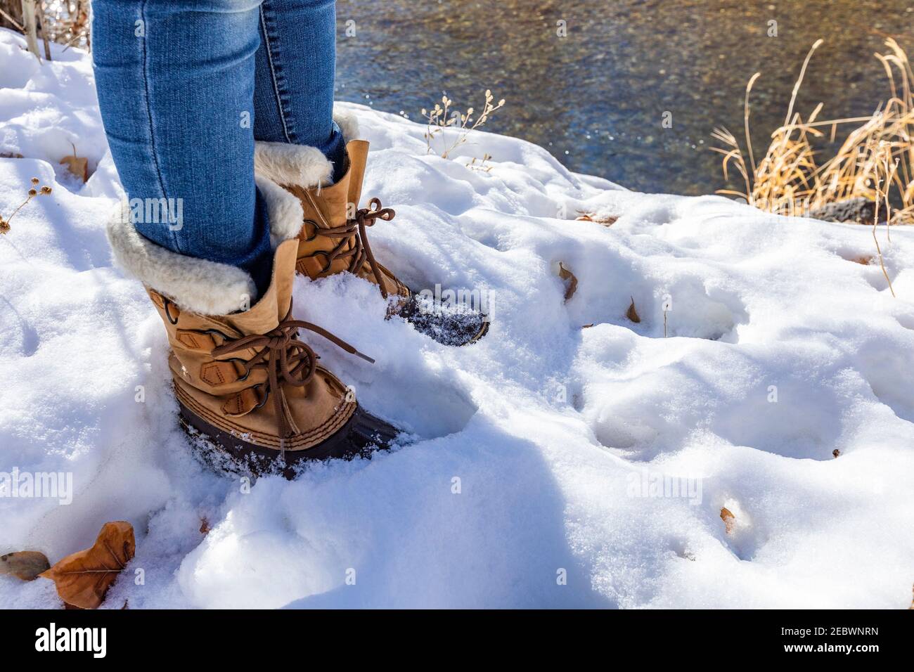 Jambes d'une femme âgée dans des bottes de randonnée debout dans la neige Banque D'Images