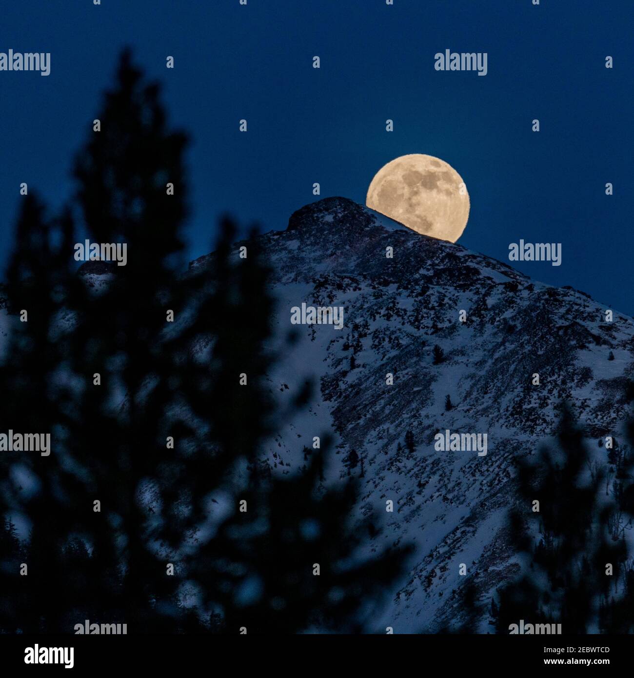 États-Unis, Idaho, Sun Valley, pleine lune qui s'élève au-dessus des montagnes Boulder en hiver Banque D'Images