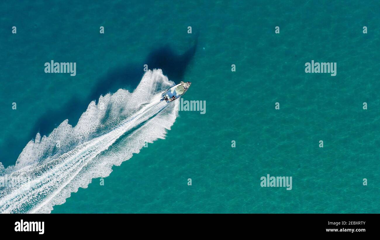 Petit bateau de pêche qui traverse la mer calme et douce, vue aérienne. Banque D'Images