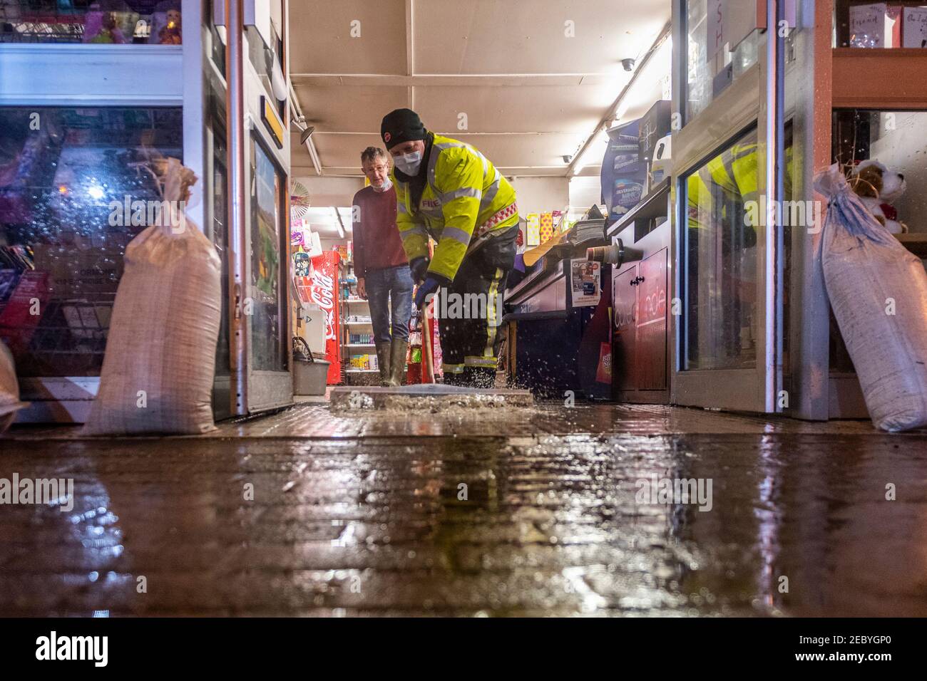Bantry, West Cork, Irlande. 13 février 2021. La place de la ville de Bantry a de nouveau inondé ce matin, en raison des hautes marées de printemps astronomiques. Trois unités de la brigade des pompiers de Bantry ont aidé les travailleurs du Conseil du comté de Cork à pomper les eaux d'inondation loin des propriétés, bien qu'un petit nombre de locaux aient été touchés par les eaux d'inondation. Un pompier assort Bill Alymer, des journalistes de la cabine, pour éliminer les eaux d'inondation de ses locaux. Photo : Andy Gibson. Banque D'Images
