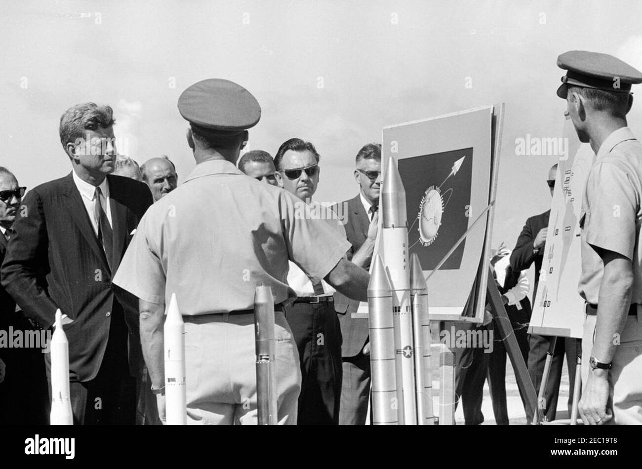 Visite d'inspection des installations de la NASA : Cape Canaveral Florida, 14:31. Le président John F. Kennedy visite le complexe Titan Launch à la station de la Force aérienne de Cape Canaveral, à Cape Canaveral, en Floride. Le directeur des opérations de sécurité de la portée avec le champ d'essai de l'est à la base aérienne de Patrick, le colonel Dan F. Thompson (au centre à gauche, de retour à la caméra), informe le président Kennedy; des modèles des missiles Titan II et Titan III sont au premier plan. Également en photo : le représentant Victor L. Anfuso (New York); les agents du Service secret de la Maison Blanche, Ron Pontius et Gerald A. u201cJerryu201d Behn. Le président Kennedy a visité Cap Banque D'Images