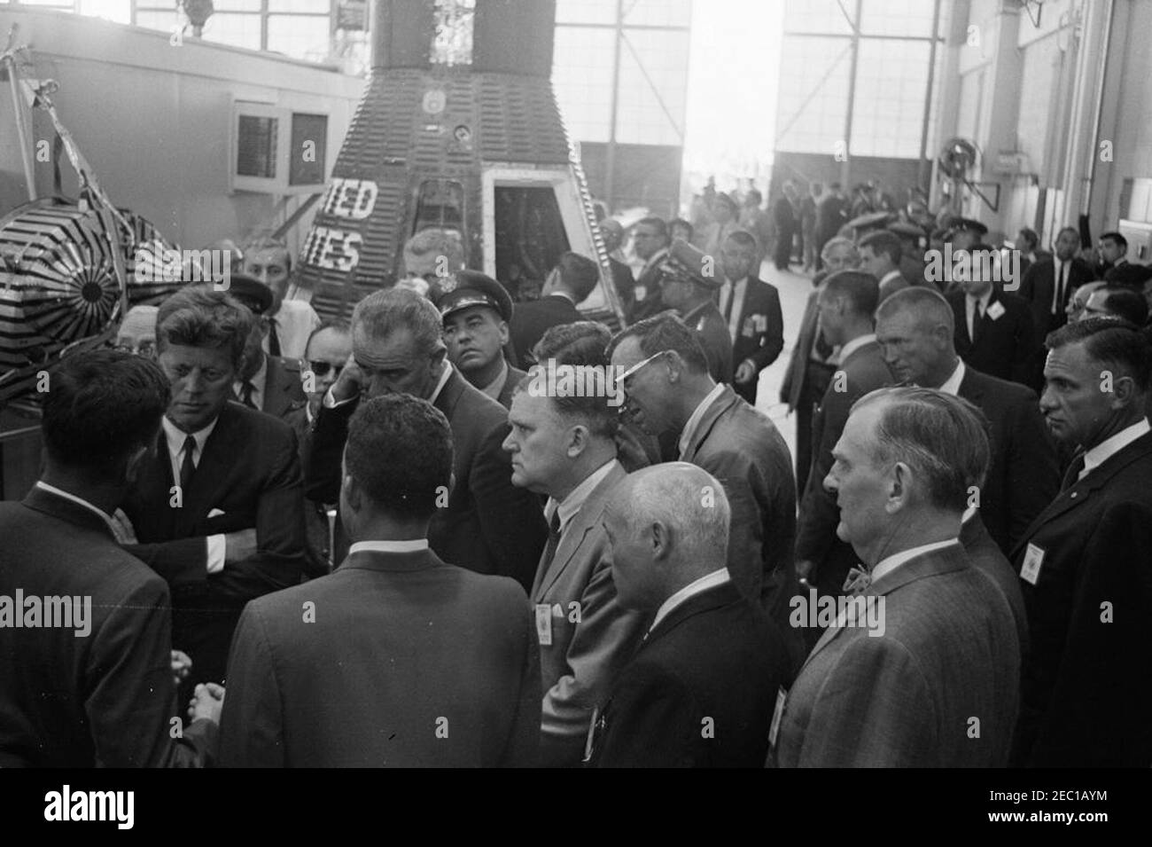 Visite d'inspection des installations de la NASA : Cape Canaveral Florida, 14:31. Le président John F. Kennedy donne avec le gestionnaire des opérations de la Floride pour le centre des engins spatiaux habités, G. Merritt Preston, et d'autres, lors d'une visite des systèmes et de l'équipement des engins spatiaux Mercury à l'intérieur de Hangar S à la station de la Force aérienne de Cape Canaveral, à Cape Canaveral, en Floride. Debout au premier plan (G-D): M. Preston (retour à la caméra); le président Kennedy; l'astronaute Major L. Gordon Cooper (retour à la caméra); le vice-président Lyndon B. Johnson; l'administrateur de la National Aeronautics and Space Administration (NASA), Dr. James E. Webb; Banque D'Images