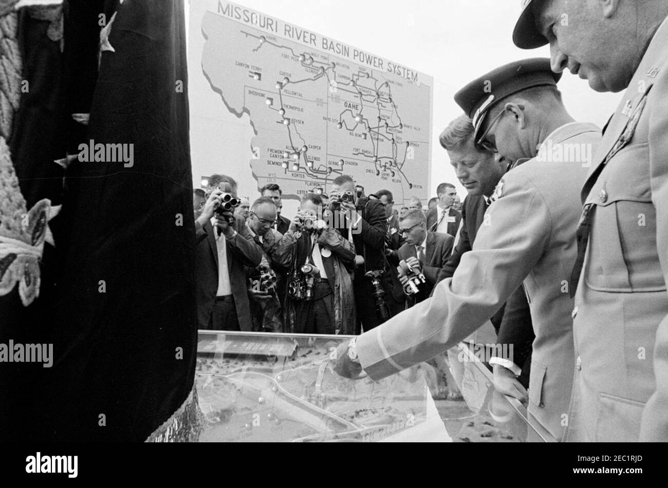 Voyage aux États de l'Ouest : Pierre, Dakota du Sud (barrage d'Oahe), 10:25. Le président John F. Kennedy voit le corps d'armée américain d'Engineersu0027 lors de la cérémonie de dédicace du barrage et du réservoir d'Oahe, sur les rives de la rivière Missouri, près de Pierre, Dakota du Sud. L'ingénieur du district d'Omaha, le colonel Harry G. Woodbury, Jr., et le chef des ingénieurs de l'armée, le lieutenant-général Walter K. Wilson, Jr., se tiennent à droite du président Kennedy. Également en photo : photographe de presse pour United Press Movietone, Thomas J. Craven, Sr. ; photographe United Press International (UPI), James K. W. Atherton ; Maison Blanche se Banque D'Images