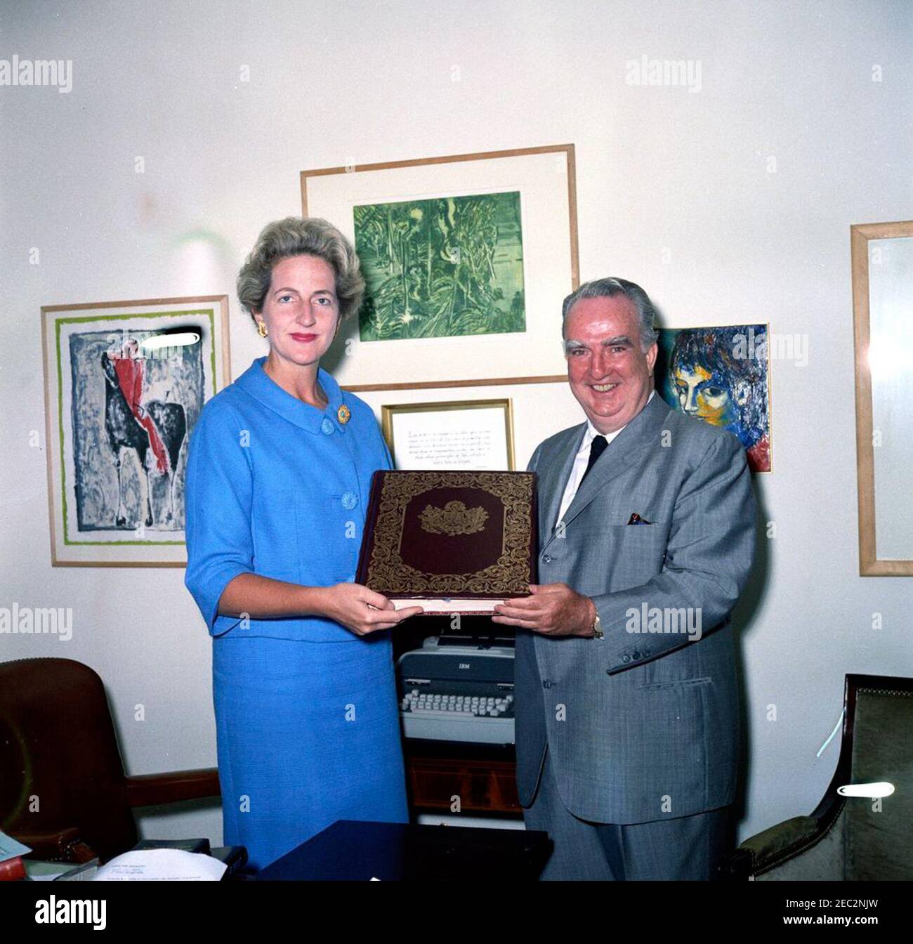 Première Ladyu2019s Secrétaire sociale Letitia Baldrige reçoit un livre pour Jacqueline Kennedy (JBK). La secrétaire sociale de la première Dame Jacqueline Kennedy, Letitia Baldrige (à gauche), reçoit un manuscrit illuminé de la Vierge de notre Dame de Guadalupe. Fred A. Joyce (à droite), directeur de la publicité pour Hilton Hotels Corporation, a présenté le livre en cadeau à Mme Kennedy au nom de Conrad N. Hilton, président de Hilton Hotels Corporation. Bureau du Secrétaire social, aile est, Maison Blanche, Washington, D.C. [les imperfections sur l'image sont originales au négatif.] Banque D'Images