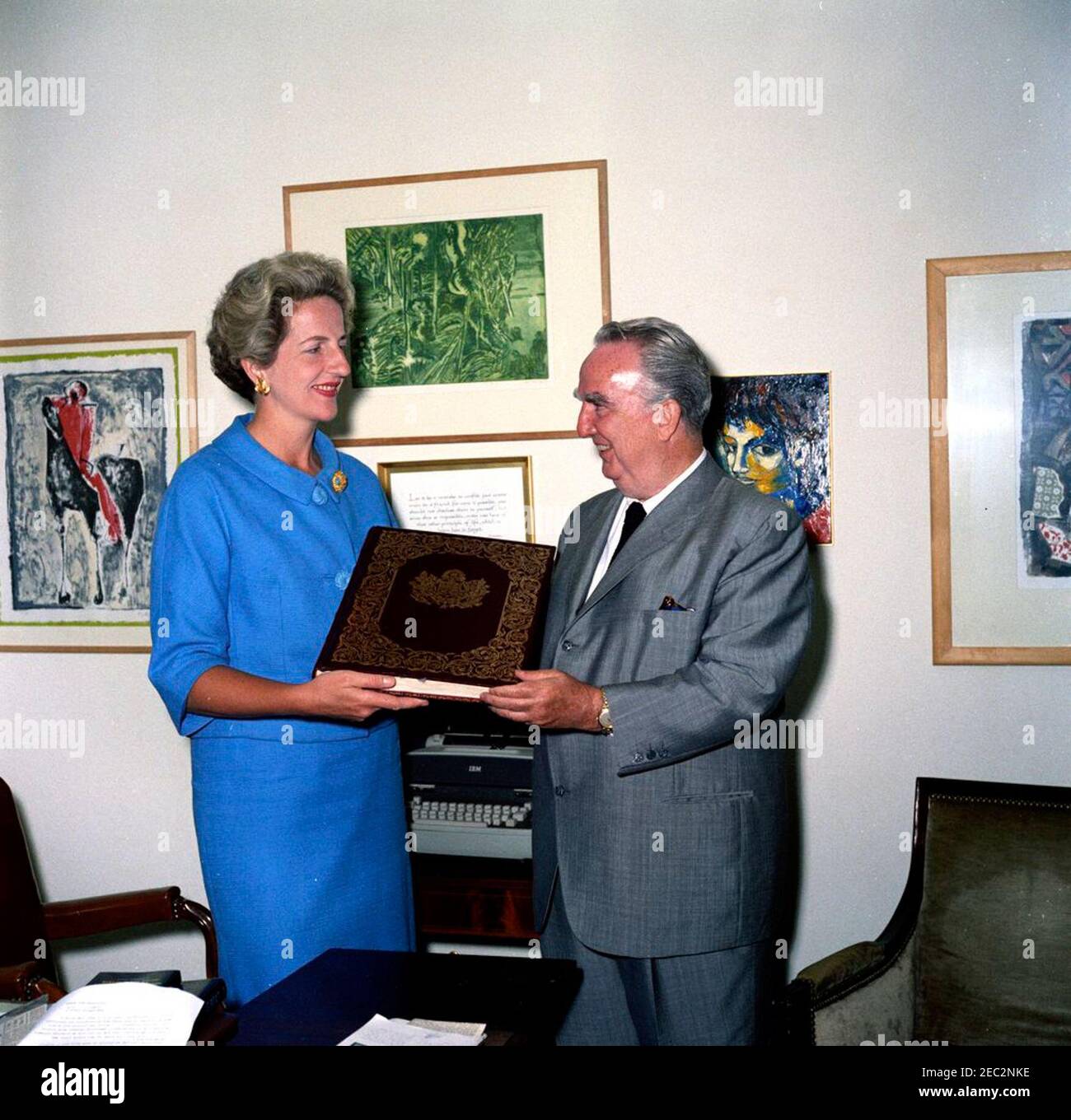 Première Ladyu2019s Secrétaire sociale Letitia Baldrige reçoit un livre pour Jacqueline Kennedy (JBK). La secrétaire sociale de la première Dame Jacqueline Kennedy, Letitia Baldrige (à gauche), reçoit un manuscrit illuminé de la Vierge de notre Dame de Guadalupe. Fred A. Joyce (à droite), directeur de la publicité pour Hilton Hotels Corporation, a présenté le livre en cadeau à Mme Kennedy au nom de Conrad N. Hilton, président de Hilton Hotels Corporation. Bureau du Secrétaire social, aile est, Maison Blanche, Washington, D.C. Banque D'Images