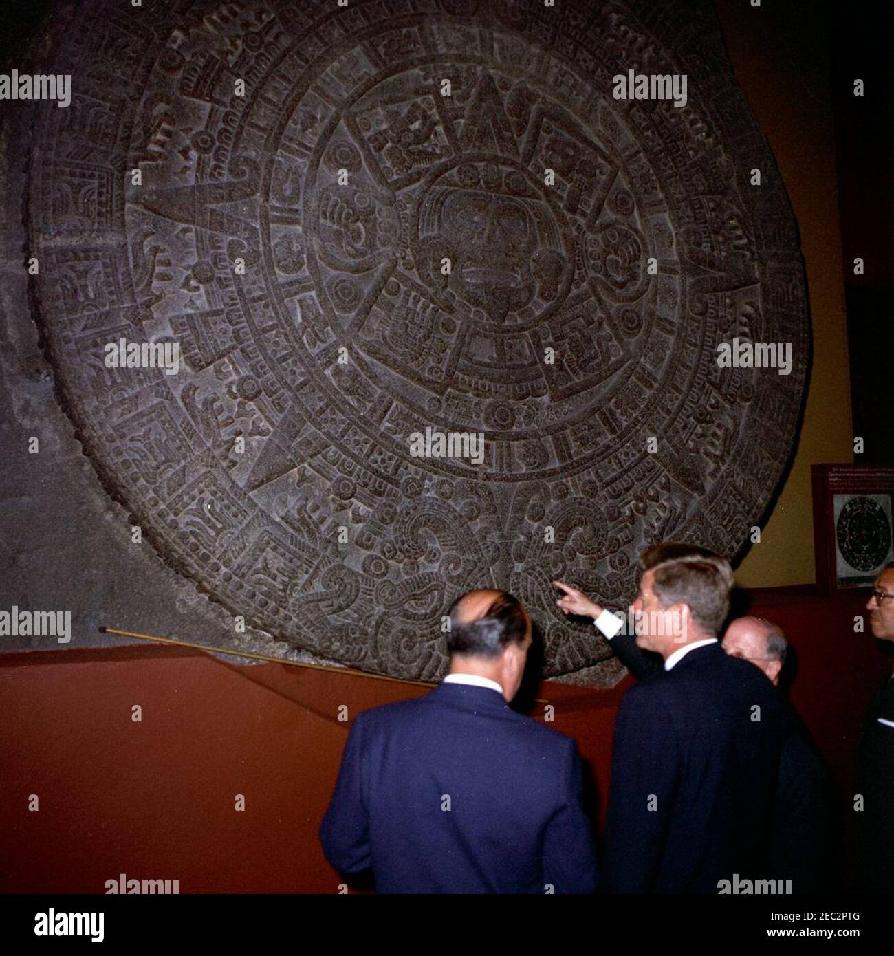 Voyage au Mexique : visite de l'Institut national d'anthropologie et d'histoire, 4:55. Le Président John F. Kennedy voit la Piedra del sol (calendrier aztèque, pierre du Soleil) lors d'une visite du Museo Nacional de Antropologu00eda (Musée national d'anthropologie) de l'Instituto Nacional de Antropologu00eda e Historia (Institut national d'anthropologie et d'histoire) à Mexico, Mexique. De gauche à droite : Chef du Département culturel de l'Instituto Nacional de Antropologu00eda e Historia, Joaquu00edn Cortina Goribar; Président Kennedy; non identifié; Directeur de l'Instituto Nacional de Antropo Banque D'Images