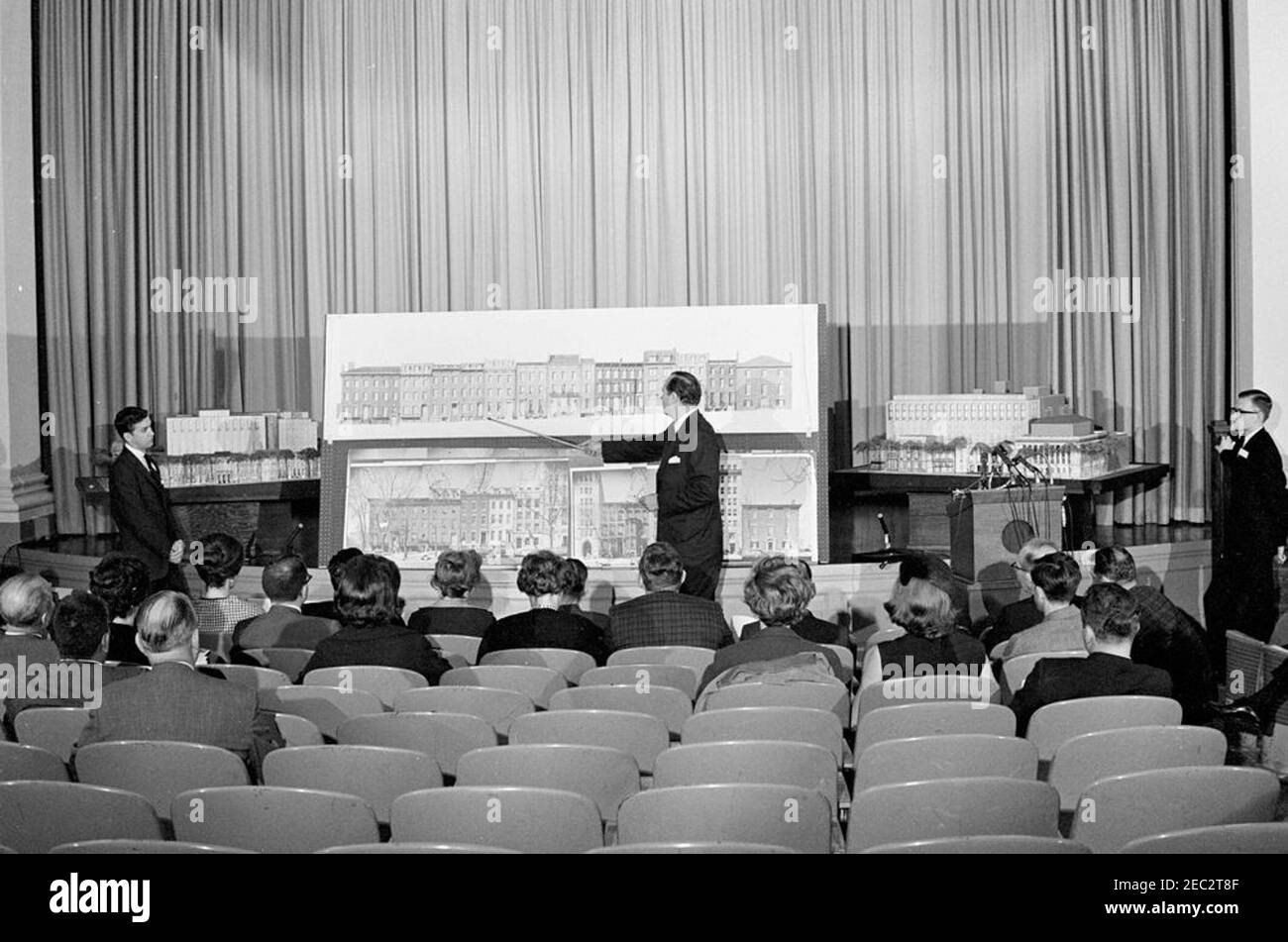 La première dame Jacqueline Kennedy (JBK) participe au dévoilement des plans de reconstruction de Lafayette Square. La première dame Jacqueline Kennedy assiste à un aperçu de la presse des plans historiques de préservation et de réaménagement de Lafayette Square, Washington, D.C.; l'architecte du réaménagement de Lafayette Square, John Carl Warnecke (centre, face à face), fait des remarques. Mme Kennedy (à gauche, de retour à la caméra) est assise à la première rangée du public. Auditorium du bâtiment administratif des services généraux, Washington, D.C. Banque D'Images