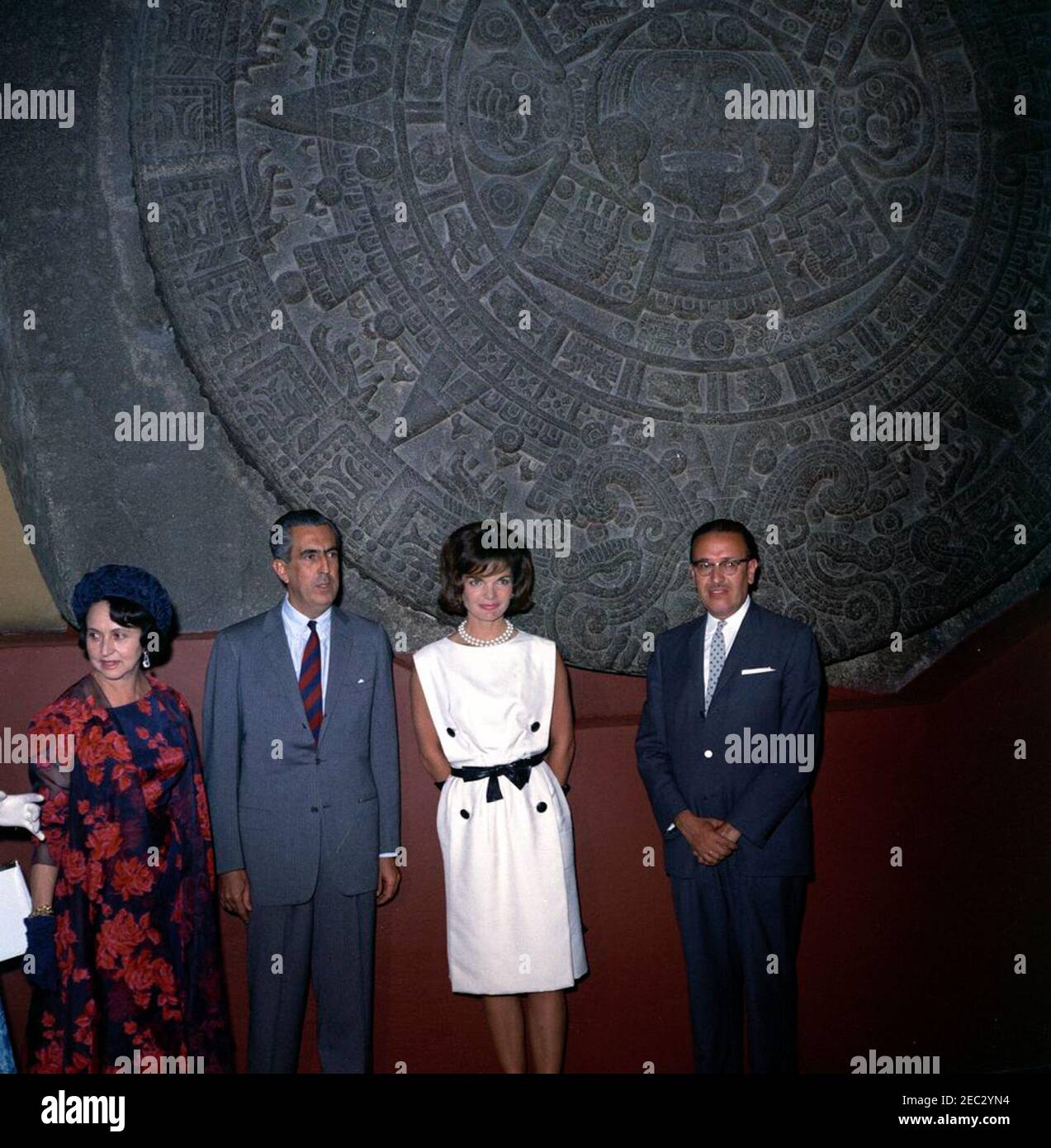 Voyage au Mexique : la première dame Jacqueline Kennedy (JBK) visite l'Institut national d'anthropologie u0026 Histoire. La première dame Jacqueline Kennedy pose devant la Piedra del sol (calendrier aztèque, pierre du Soleil) lors d'une visite du Museo Nacional de Antropologu00eda (Musée national d'anthropologie) de l'Instituto Nacional de Antropologu00eda e Historia (Institut national d'anthropologie et d'histoire) à Mexico, Mexique. De gauche à droite : première Dame du Mexique, Eva Su00e1mano de Lu00f3pez Mateos; sous-directrice de l'Instituto Nacional de Antropologu00eda e Historia, Dr. Ignacio Bernal; Mme Banque D'Images