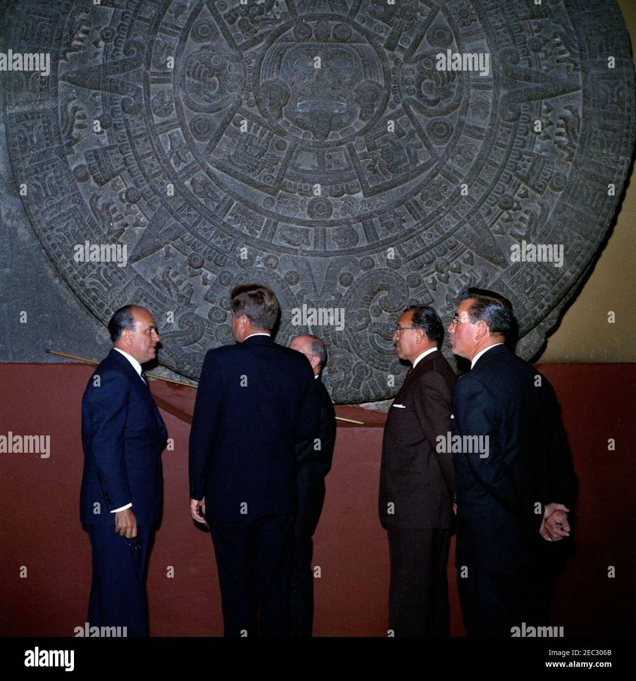 Voyage au Mexique : visite de l'Institut national d'anthropologie et d'histoire, 4:55. Le Président John F. Kennedy voit la Piedra del sol (calendrier aztèque, pierre du Soleil) lors d'une visite du Museo Nacional de Antropologu00eda (Musée national d'anthropologie) de l'Instituto Nacional de Antropologu00eda e Historia (Institut national d'anthropologie et d'histoire) à Mexico, Mexique. De gauche à droite : Chef du Département culturel de l'Instituto Nacional de Antropologu00eda e Historia, Joaquu00edn Cortina Goribar; Président Kennedy; non identifié (pour la plupart caché); Directeur de l'Instituto NAC Banque D'Images