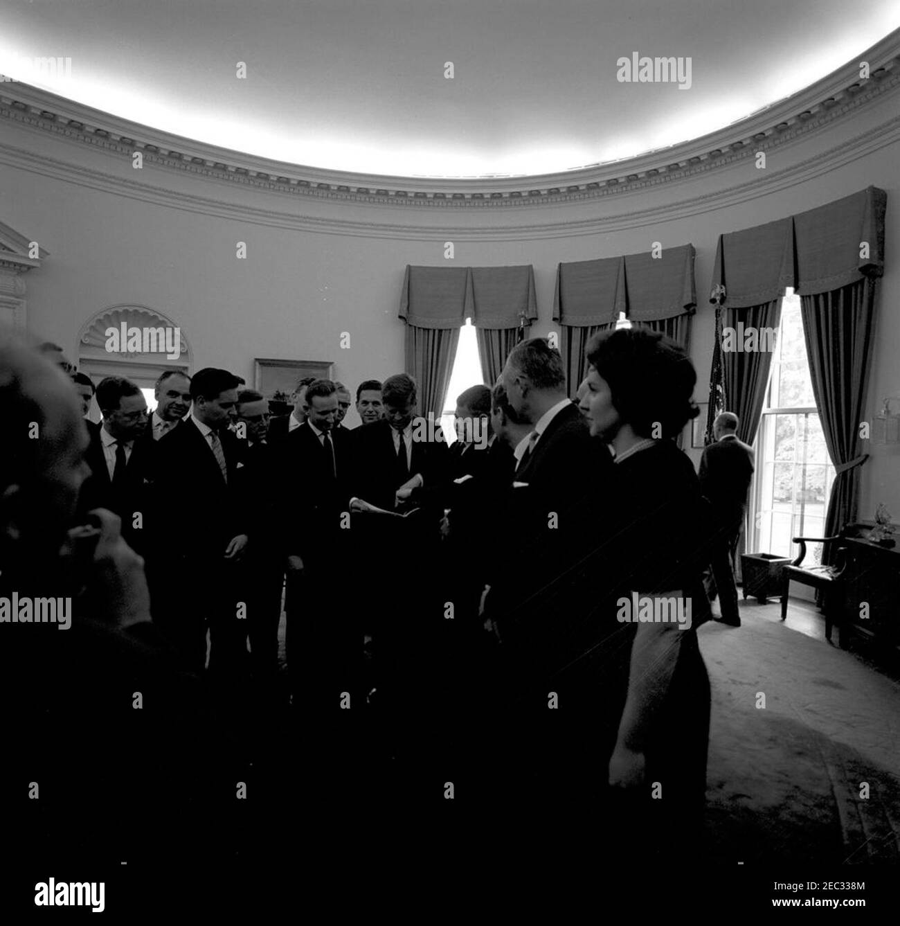 Visite des membres du Club politique de l'Académie évangélique de Bavière, Allemagne, 13:04. Des membres du Club politique de l'Académie évangélique (luthérienne) de Tutzing, en Bavière, en Allemagne (Evangelische Akademie Tutzing) présentent au Président John F. Kennedy une sculpture d'un chérubin. Mary Kinsella, membre du personnel du sénateur Eugene McCarthy, se trouve à droite; les membres de l'académie ne sont pas identifiés. Oval Office, Maison Blanche, Washington, D.C. [Voir aussi Mo 63.1907, u201cSculpture d'un Cherubu201d] Banque D'Images