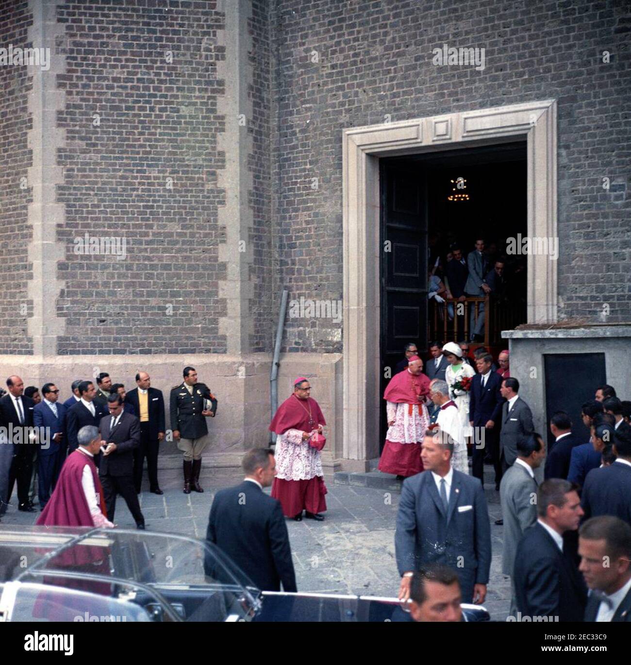 Voyage au Mexique: Le Président Kennedy u0026 la première Dame Jacqueline Kennedy (JBK) assiste à la messe à la Basilique de Guadalupe, 10:05. Le président John F. Kennedy et la première dame Jacqueline Kennedy marchent vers la limousine présidentielle (Lincoln-Mercury Continental avec bulle-top) après la messe à la Basu00edlica de Nuestra Seu00f1ora de Guadalupe (Basilique de notre-Dame de Guadalupe) à Mexico, Mexique. Également en photo : Archiprêtre de la Basu00edlica, Monseigneur Gregorio Aguilar; Archevêque de Mexico, Miguel Daru00edo Miranda y Gu00f3mez; délégué apostolique au Mexique, Archevêque Luigi Raimo Banque D'Images