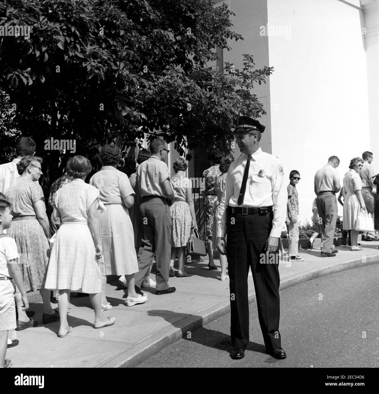 Chef de la police de la Maison Blanche, le major Ralph C. u0022Smokeyu0022 Stover, avec des visiteurs. Le chef de la police de la Maison Blanche, le major Ralph C. u0022Smokeyu0022 Stover, observe que les visiteurs attendent devant l'entrée du Visitoru2019s. Aile est, Maison Blanche, Washington, D.C. Banque D'Images